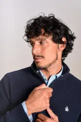 Sweater de punto acanalado color azul marino, con cuello alto y cierre frontal parcial. Presenta el logo de la marca bordado en el pecho y puños con terminación elástica.
