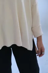 Sweater de punto en color crudo, con escote en V, mangas tres cuartos con puños acanalados y diseño holgado.