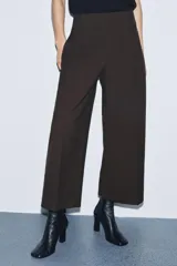 Pantalón de tiro medio confeccionado en viscosa, con corte recto y largo tobillero. Presenta cintura con trabillas, bolsillos laterales y bolsillos de vivo en la parte trasera. Cierre frontal mediante cremallera, botón y ganchos metálicos.