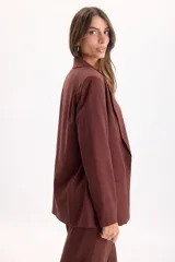 Blazer sastrero de lino color marrón, de líneas clásicas con solapas, bolsillos delanteros con solapa y caída liviana.