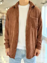Sobrecamisa de pana color marrón chocolate, de manga larga, con cuello camisero, cierre frontal con botones y un bolsillo aplicado en el pecho.
