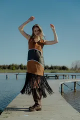 Vestido corto marrón con detalles en negro y flecos en el ruedo. Confeccionado artesanalmente con diferentes cueros bordados a mano y espalda en tejido de hilado.