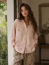 Camisa de lana color rosado, de corte oversize, con mangas largas, bolsillos frontales con solapa y cierre de botones.