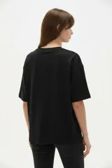 Remera blanca de algodón de manga corta, con cuello redondo y corte holgado. Presenta estampado frontal de un lazo con detalles de brillos y la frase 'Made of sweetness'.