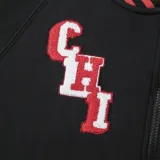 Campera negra con detalles en rojo y blanco, con cierre frontal y bolsillos laterales. Presenta el logo de los Chicago Bulls en el pecho y letras en el brazo izquierdo.