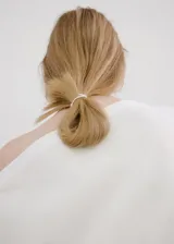 Blusa blanca de algodón con cuello asimétrico, detalles fruncidos, manga larga y cierre de cremallera lateral.
