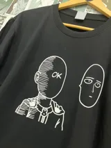 Remera negra con estampado de Saitama de One Punch Man haciendo el gesto de OK y otro dibujo de su cara.