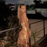 Vestido corto con estampado abstracto en tonos naranja, blanco y marrón. Diseño con escote halter y espalda descubierta.