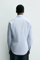 Camisa de corte slim fit confeccionada en tejido de algodón, color celeste. Cuenta con cuello abotonado, manga larga con puños ajustables mediante botón y cierre frontal con botonadura.