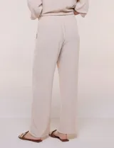 Pantalón pull-on de color beige con caída fluida, cintura elastizada fruncida, bolsillos laterales funcionales y pierna amplia de corte wide leg.