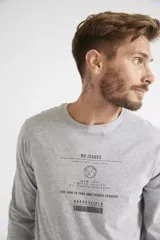 Remera de manga larga color gris melange, con cuello redondo y estampa frontal con diseño gráfico y texto.