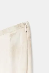 Falda midi de tiro medio con estampado floral en tonos azules y verdes sobre fondo beige. Presenta una abertura frontal en el bajo y cierre lateral con cremallera oculta.
