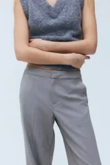 Pantalón sastrero gris de tiro alto, con cierre y corchete ocultos, piernas rectas con raya marcada al frente y en la espalda, y bolsillos laterales al bies.