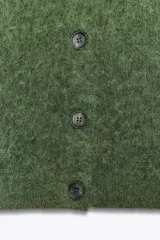 Chaqueta de punto de textura peluda en color verde, con cuello redondo, manga corta y cierre frontal con botones a tono.