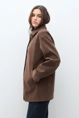 Chaqueta color chocolate de simil gamuza, con cuello camisero, botones frontales y bolsillos laterales.
