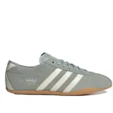 Championes Adidas Tokyo de perfil bajo, confeccionados en gamuza color verde con detalles en blanco y suela de goma marrón. Presentan las clásicas tres tiras laterales y la inscripción 'adidas TOKYO' estampada en dorado.
