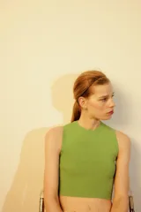 Top crop de tejido de punto color beige claro, con cuello redondo y manga sisa. Presenta acabados en rib en el cuello, sisas y bajo.