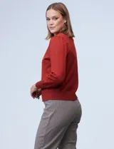 Cardigan rojo tejido en hilado fino, con escote en V y abertura central con botones metálicos.