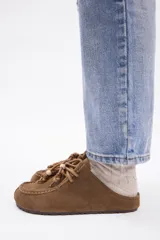 Zueco de cuero vacuno color marrón, con diseño de puntera reforzada y cordones decorativos con cuentas de madera en el empeine.