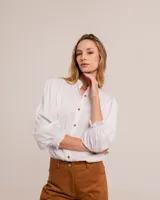 Blusa celeste de cuello mao y mangas abullonadas con puños elásticos. Tiene tajos laterales y botones en la delantera.