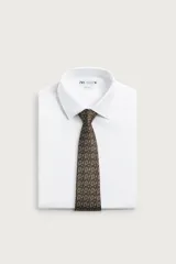 Corbata ancha de seda color marrón oscuro con estampado de raquetas de tenis y volantes. Confeccionada en tejido jacquard con forro de seda.