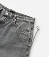 Pantalón de jean estilo baggy balloon, de corte holgado con volumen en las piernas y cintura fija con trabillas. Presenta costuras a contratono y detalle de cadena metálica lateral.
