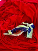 Sandalias de cuero gamuzado color azul, con taco ancho y tiras cruzadas en el empeine decoradas con flecos de cuentas. Cuentan con pulsera regulable al tobillo con hebilla metálica.