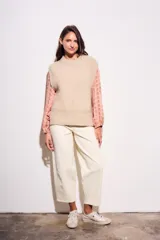 Chaleco de punto color beige con cuello alto y sisas amplias.