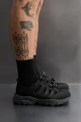 Sandalia deportiva negra con aberturas laterales para ventilación, puntera reforzada, ajuste con cordones y suela de goma.