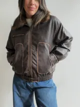 Campera estilo bomber de efecto cuero en color chocolate, con cuello de pelo sintético desmontable, cierre frontal, bolsillos laterales amplios y cintura elástica con ajuste lateral.