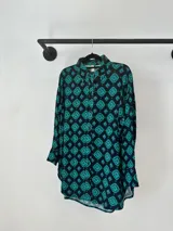 Camisa de corte oversize y silueta holgada, con mangas largas y cierre frontal de botones. Presenta un estampado geométrico de rombos en tonos verde esmeralda, violeta y negro.
