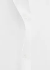 Camisa blanca de algodón, de corte clásico con cuello camisero, manga larga y cierre frontal con botones.