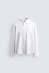 Camisa de corte regular fit confeccionada en tejido de algodón con diseño de rayas verticales. Presenta cuello abotonado, manga larga con puños abotonados, bolsillo plastrón en el pecho y cierre frontal con botones.