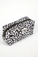 Neceser rectangular acolchado con estampado animal print blanco y negro, cierre superior con cremallera y parche con logo de la marca.