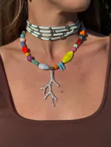 Collar corto con cuentas de cristal checo, cerámica y piedras reconstituidas de colores. Incluye separadores de acero quirúrgico y un dije plateado en forma de coral. Se cierra con cadena de acero quirúrgico para regular el largo.