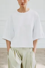 Camiseta de algodón con cuello redondo, manga tres cuartos con detalle de botón metálico y bajo recto.