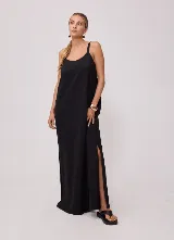 Vestido largo negro de corte holgado, con tirantes finos, escote redondo y aberturas laterales en el bajo.