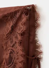 Falda midi recta de satén color marrón, con tiro regular y detalle de puntilla en el ruedo y el lateral.