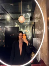 Blazer negro de corte sastrero con diseño de rayas diplomáticas verticales, cierre frontal de un botón y bolsillos laterales con solapa.