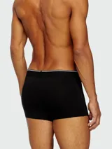 Pack de tres bóxers Diesel, uno negro con elástico blanco y logo, y dos con estampado de camuflaje en tonos grises y negros.