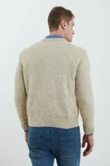 Sweater de tejido de punto color beige claro, con diseño de trenzas (aranes) en el frente y mangas de punto liso. Tiene cuello redondo.