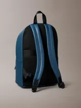 Mochila Calvin Klein de poliuretano texturizado en color azul, con compartimento principal con cierre de doble cremallera, bolsillo frontal con cierre, asa superior y tirantes ajustables. Incluye detalle de logo metálico de la marca en el frente.