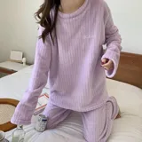 Conjunto de pijama de dos piezas confeccionado en tela de plush texturizada con diseño de rayas verticales en relieve. Incluye una remera de manga larga con cuello redondo y un pantalón de corte holgado. La remera presenta un pequeño bordado decorativo en el pecho.