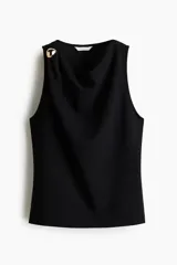 Musculosa negra confeccionada en punto de crepé, con diseño sin mangas, elegante escote drapeado y un aplique metálico dorado decorativo en el hombro derecho.