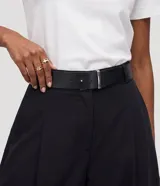 Pantalón barrel de viscosa color negro, de corte ancho con diseño redondeado en las piernas y bajo ajustado. Presenta pinzas laterales, trabillas y un cinturón fijo de PU con hebilla metálica.