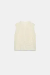 Blusa sin mangas color crema, con cuello subido y detalles de puntilla combinada a tono. Cierre frontal con botones.
