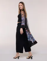 Cardigan tipo kimono largo de tul blanco semitransparente, con frente abierto y mangas largas. Presenta vistosos bordados florales multicolor en mangas, dobladillo y laterales.