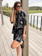 Conjunto compuesto por camisa de manga corta y short, ambos en color azul marino con estampado geométrico de inspiración paisley y elementos marinos en tono crudo.