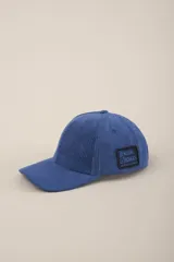 Gorra azul de pana con visera curva y parche con el logo de la marca Benson & Thomas en el lateral.