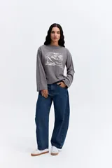 Remera de manga larga color gris, con cuello redondo y estampa gráfica abstracta en el frente.